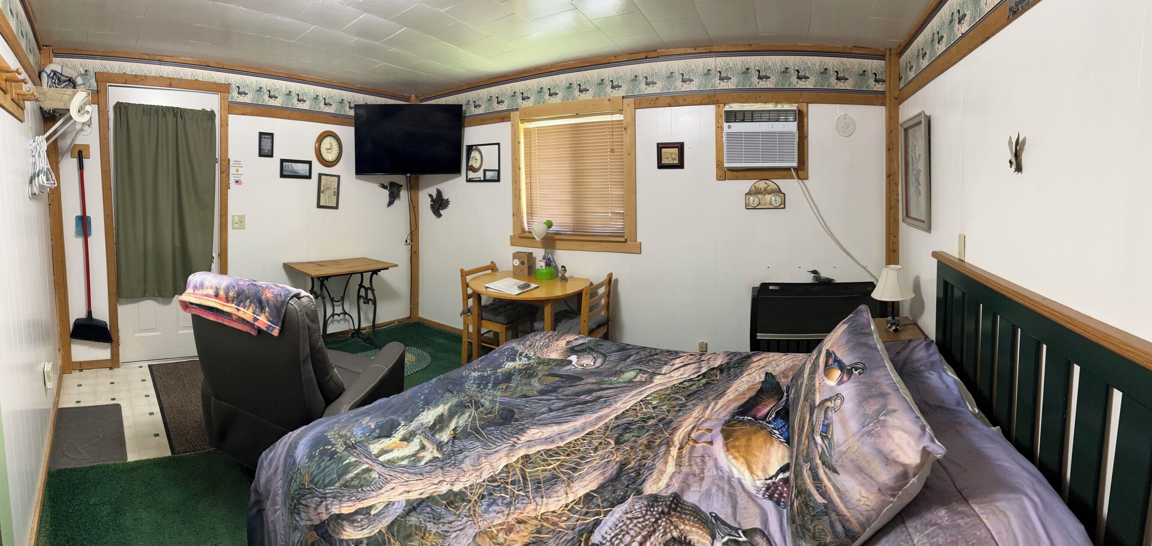 Une chambre à coucher avec un lit, un bureau, une chaise, un téléviseur et une fenêtre avec des stores.