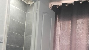 A bathroom with a toilet, a shower, and a door. - Hôtel des Andelys (Paris)
