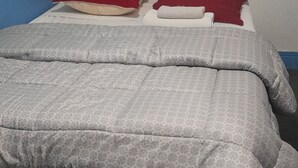 A bed with a grey patterned duvet, two red pillows, and a white pillow. - Hôtel des Andelys (Paris)