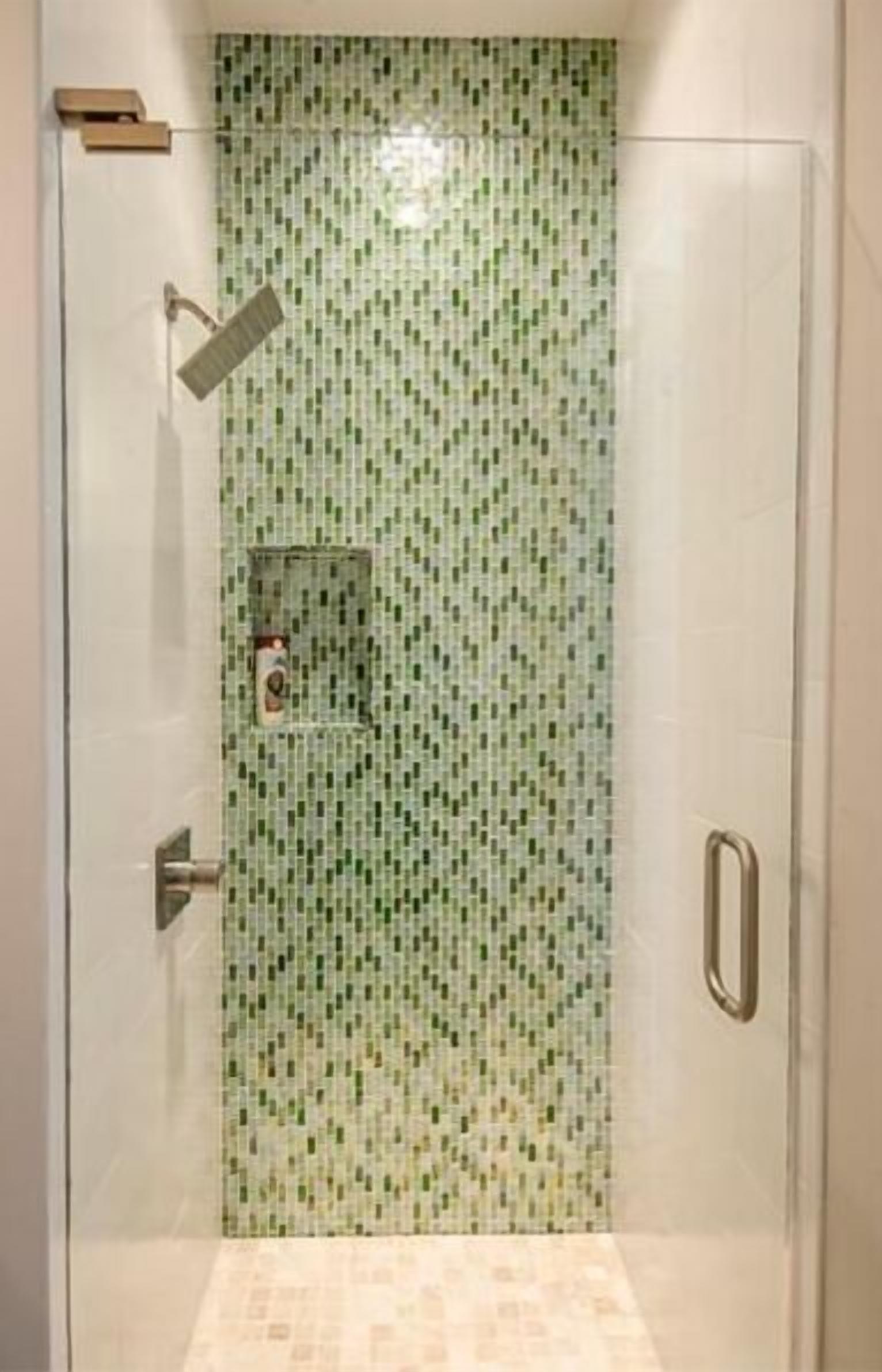 Une douche entièrementClose avec un mur recouvert de mosaïques.
