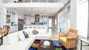 A spacious living area with a white sofa, a wicker chair, and a coffee table.