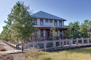 A two-story building with a red and white exterior, a metal roof, and a wooden deck leading to the entrance.