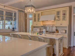 A spacious kitchen with a central island, white cabinetry, and a modern chandelier. - Southern Accent House (Port St. Joe)