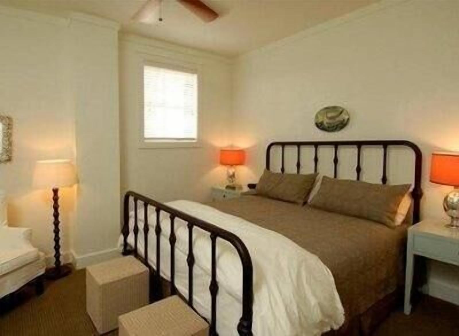 A bedroom with a bed, bedside tables, a window, and a ceiling fan.