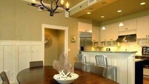 A modern kitchen with white cabinets, a central island, and pendant lighting. - Morning Glory 309 (Port St. Joe)