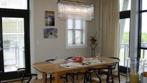 A dining area with a wooden table, six chairs, and a chandelier. - Morning Glory 311 (Port St. Joe)