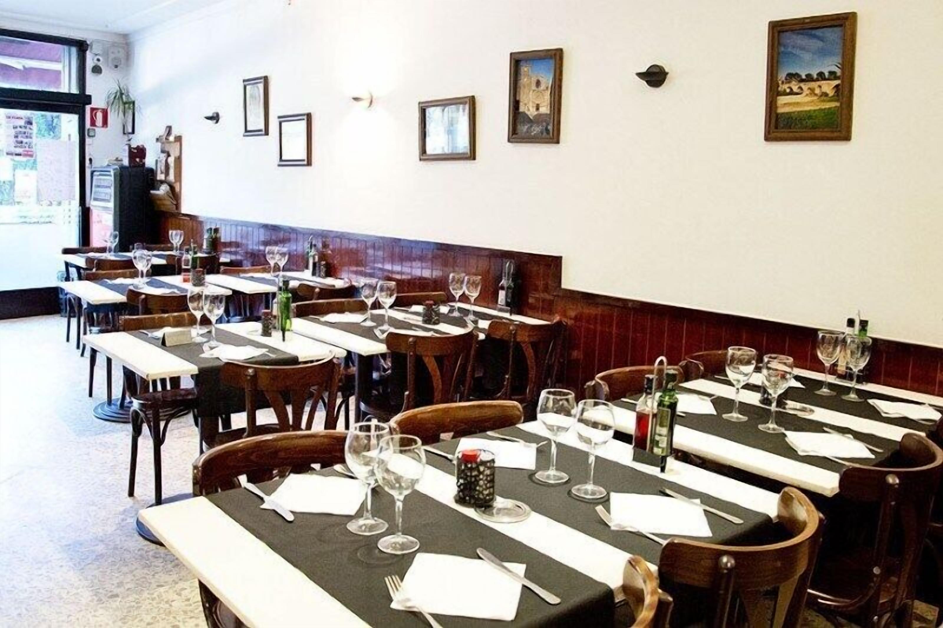 Ein Restaurant mit mehreren Tischen, gedeckt zum Essen, mit einer Mischung aus Holzstühlen und Bänken.