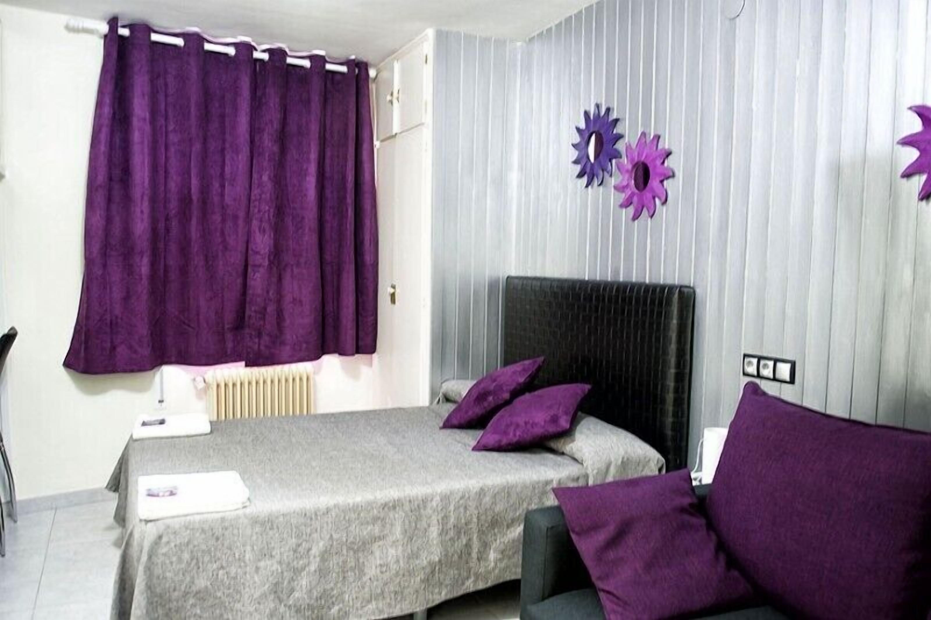 Une chambre à coucher avec un lit, des rideaux violets et des éléments décoratifs sur les murs.