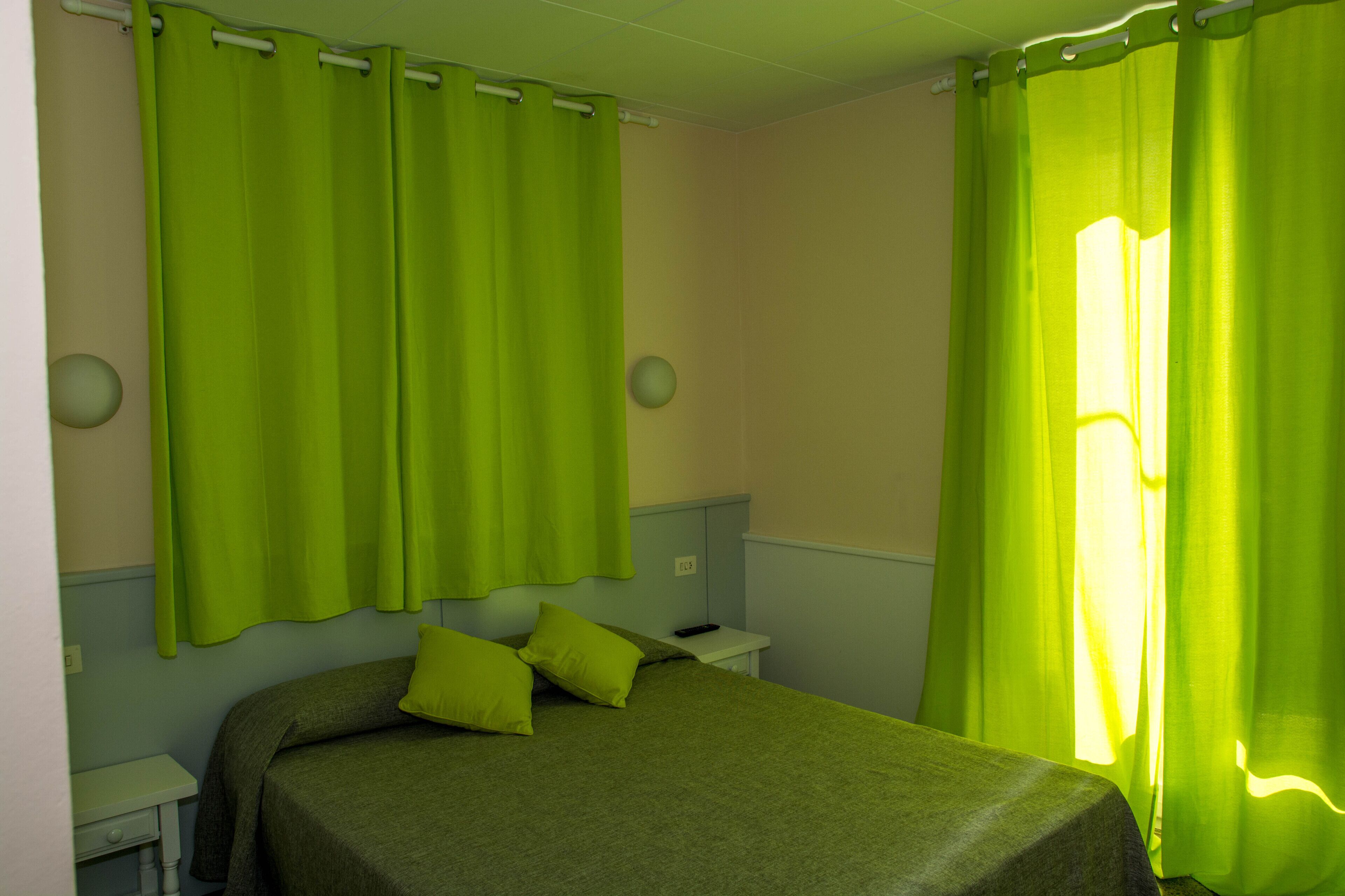 Um quarto com uma cama, uma mesa de cabeceira e cortinas.