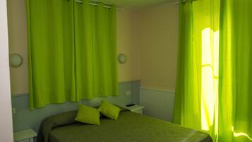 Um quarto com uma cama, uma mesa de cabeceira e cortinas.