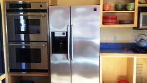 Eine kompakte Küche mit Edelstahl-Kühlschrank, zwei Backöfen und Mikrowelle.