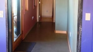 Ein Flur mit einer zurueckfuehrenden Fuehrung zu einem Zimmer, einer weiteren Fuehrung am Ende des Flurs und einer Leuchte an der Decke.