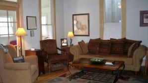 A living room with a sofa, armchair, and coffee table. There are two lamps, a framed picture on the wall, and a window with curtains. - Scott s Downtown 1 Bedroom Holiday Home By Pinon Vacation Rentals (Salida)