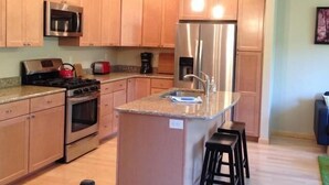 A modern kitchen with wooden cabinets, stainless steel appliances, and a granite countertop.