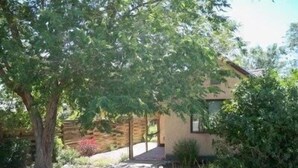 Une maison moderne avec un toit en pente, un garage apparent et un jardin bien entretenu, agrémenté de diverses plantes et d’un arbre.