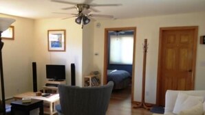 Un salon équipé d’un ventilateur de plafond, d’une télévision, d’un canapé et d’un fauteuil.
