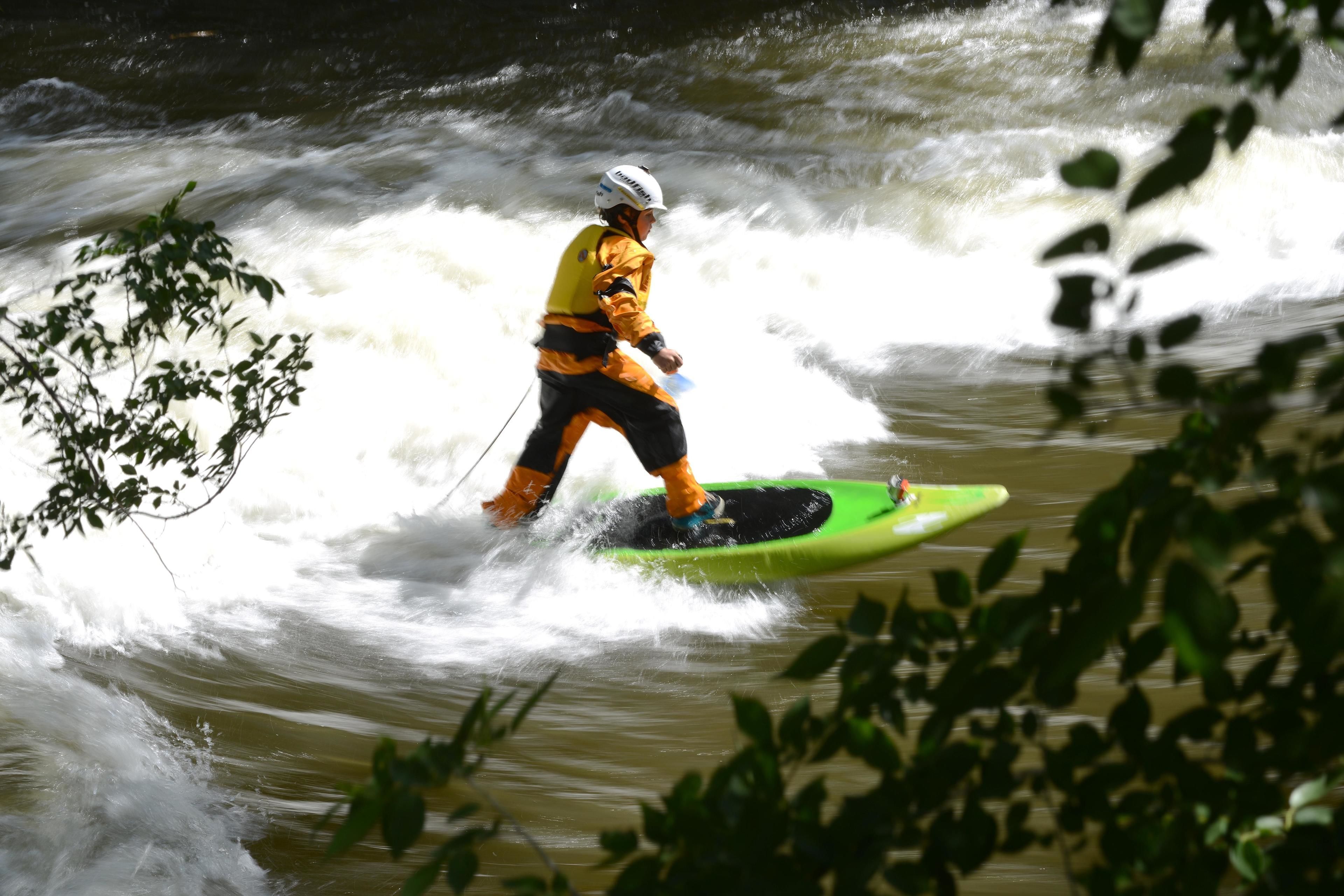 Une personne est assise dans un kayak vert sur une rivière.