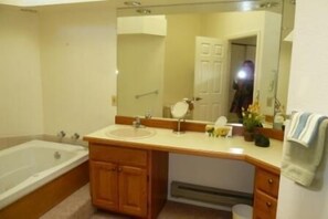 A bathroom with a bathtub, sink, vanity, and mirror. - Villa on the Green 2 Bedroom Holiday Home By Pinon Vacation Rentals (Salida)