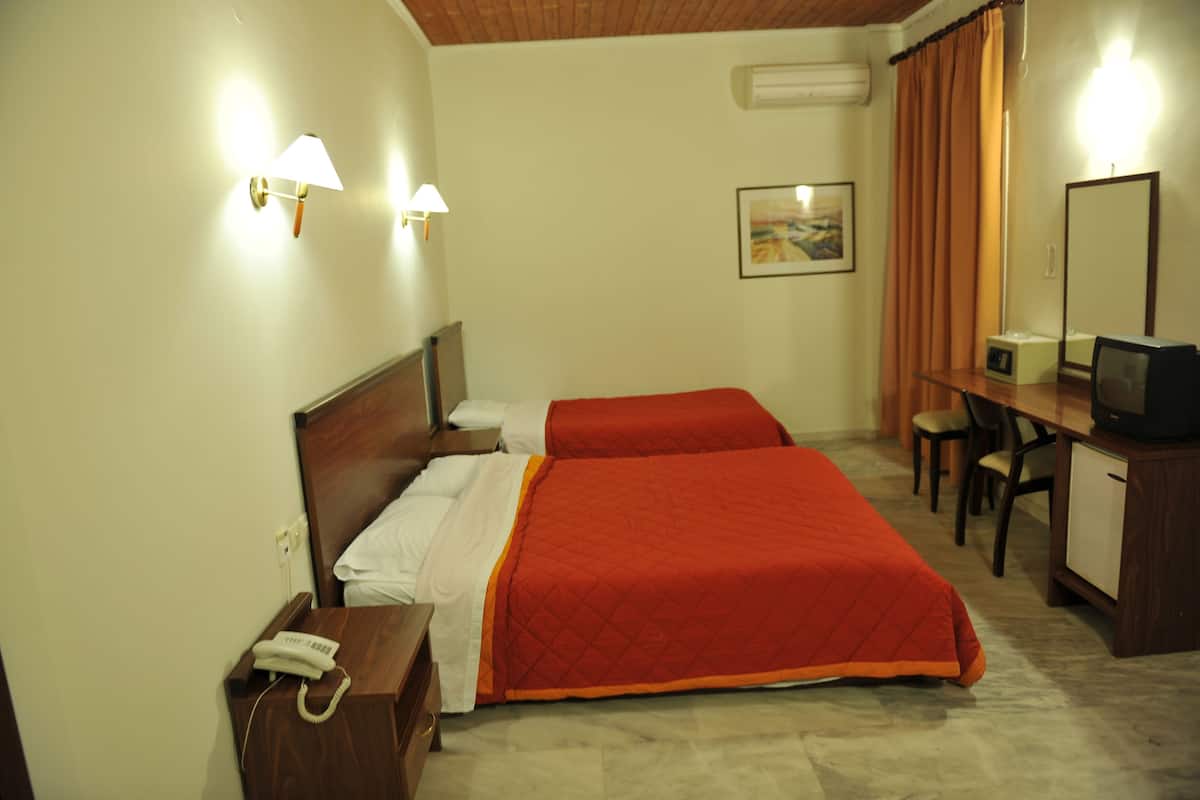 A hotel room with two beds, a desk with a chair, a television, and a telephone.