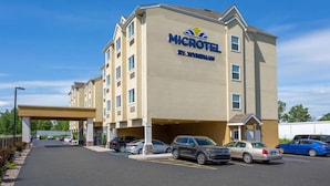 Un hotel Microtel by Wyndham con un estacionamiento y varios coches aparcados al frente.