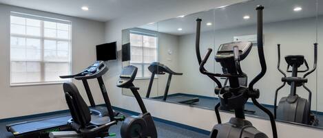 Un gimnasio con cintas de correr, elípticas y bicicletas estáticas.