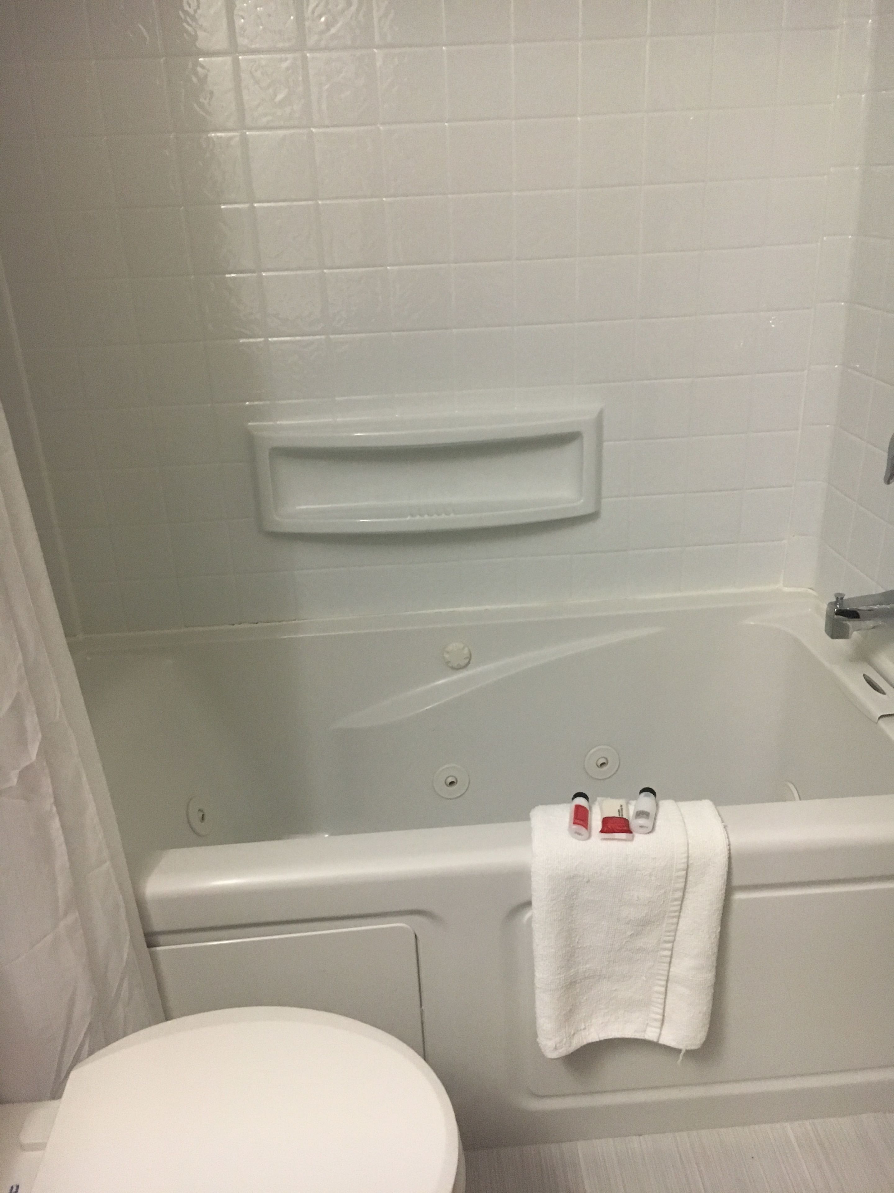 A bathroom with a white bathtub, a toilet, and a towel rack with a towel.