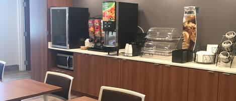 A modern cafe with wooden tables and chairs, a coffee machine, and a refrigerator.