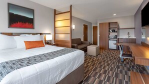 Una habitación de hotel con una cama grande, un escritorio, una kitchenette y un televisor.