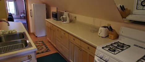 Una cocina compacta con estufa, microondas, fregadero y armarios.