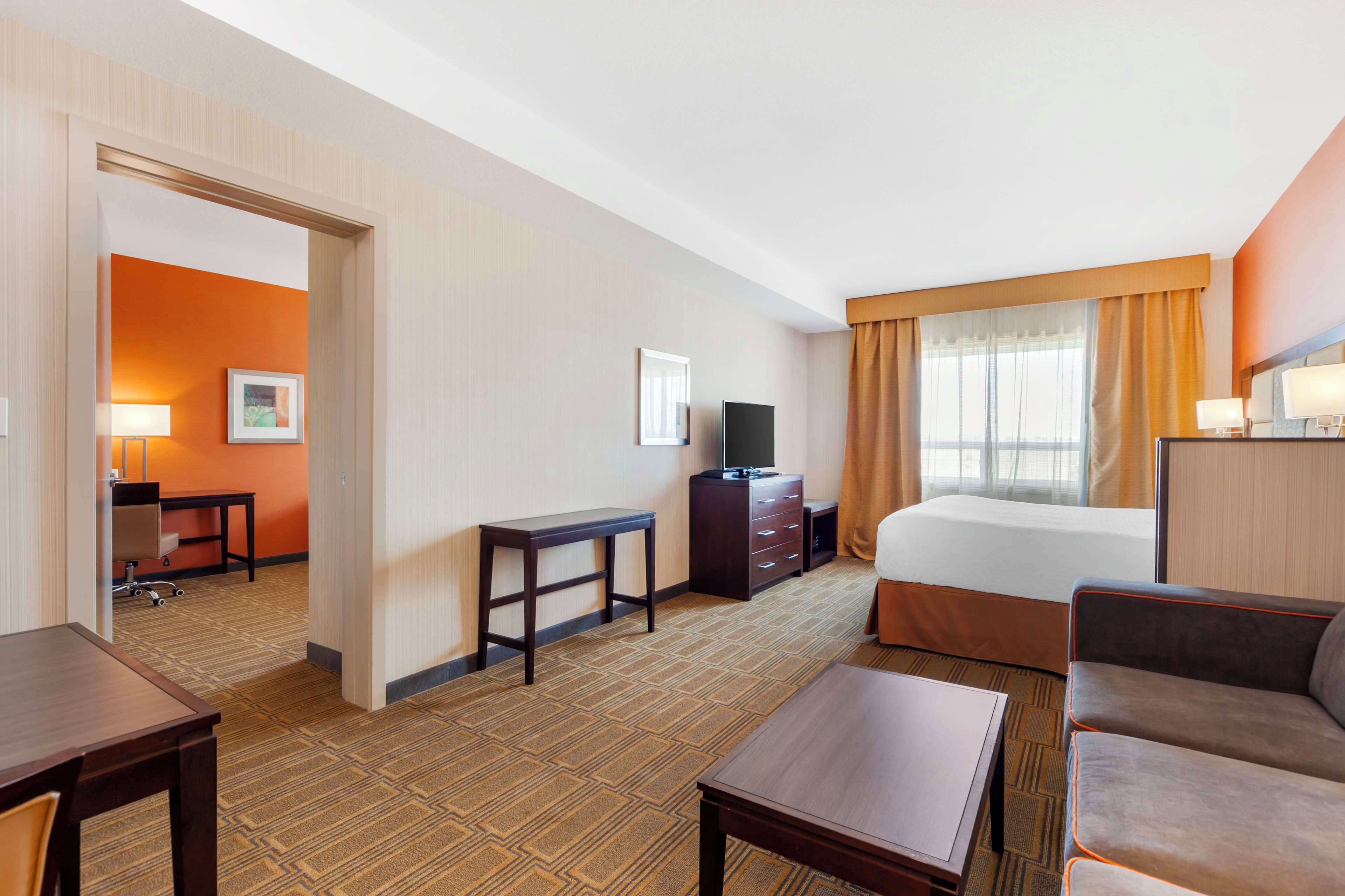Ein Hotelzimmer mit Bett, Schreibtisch, Fernseher, Sofa und kleinem Tisch.