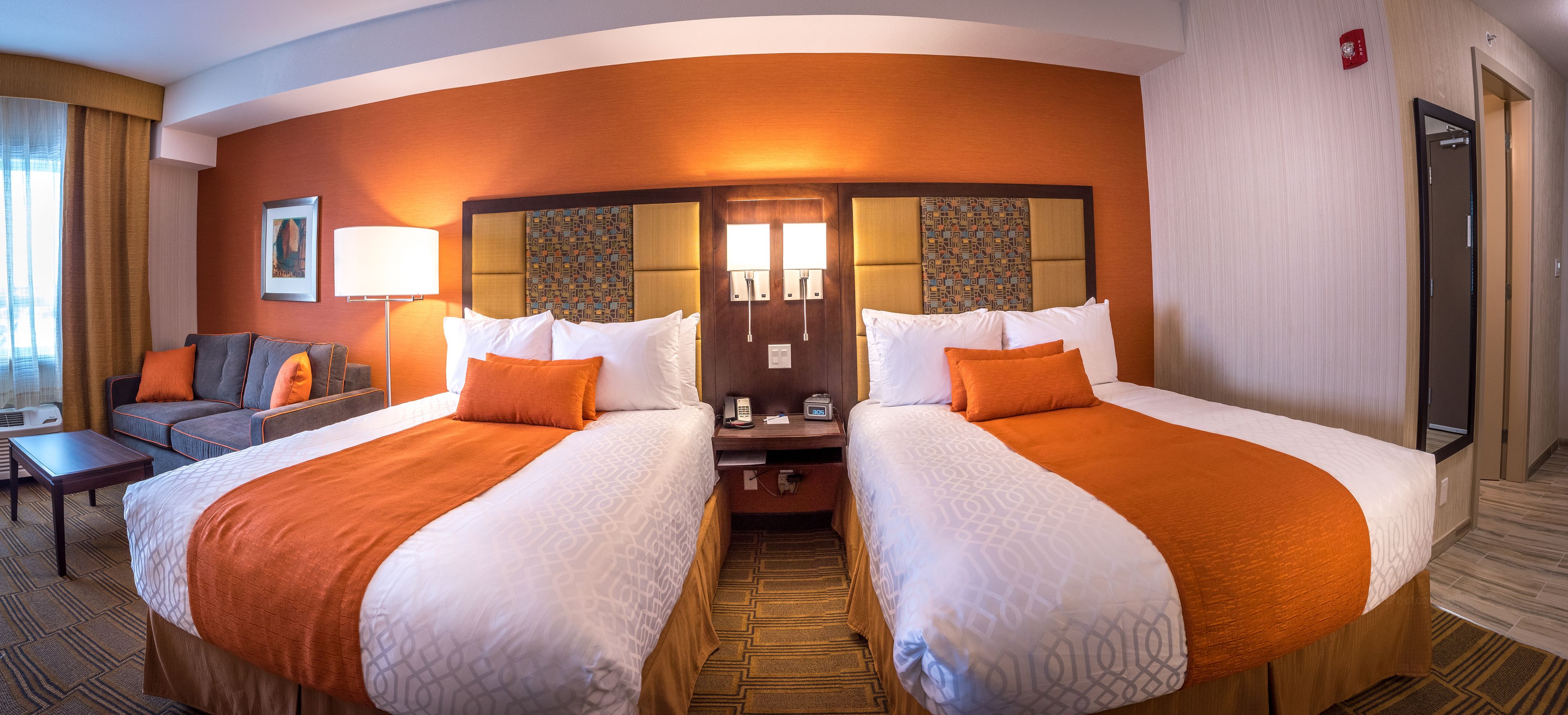 Ein Hotelzimmer mit zwei Betten, einem Schlafsofa, einem Schreibtisch und einem Nachttisch.