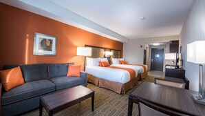 A hotel room with a sofa, two beds, a desk, and a mirror. - Best Western Plus Chateau Fort St. John (Fort St. John)