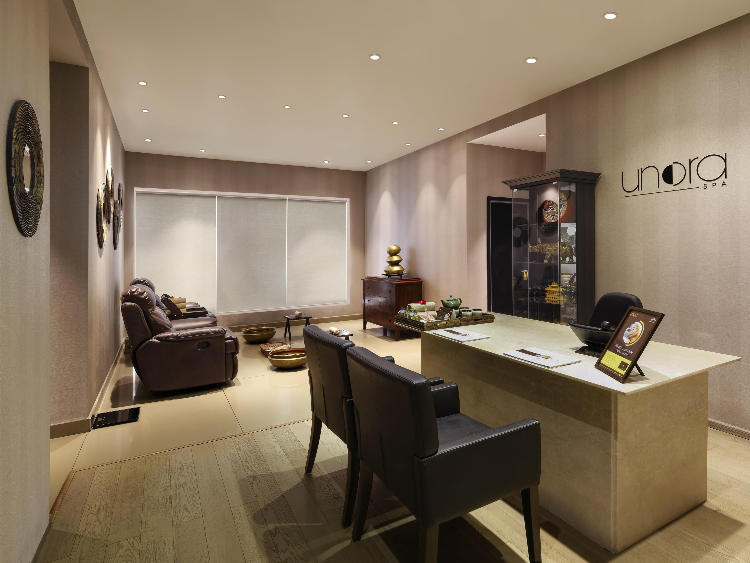 A modern spa interior with a reception desk, massage chairs, and decorative items.