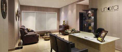 A modern spa interior with a reception desk, massage chairs, and decorative items.