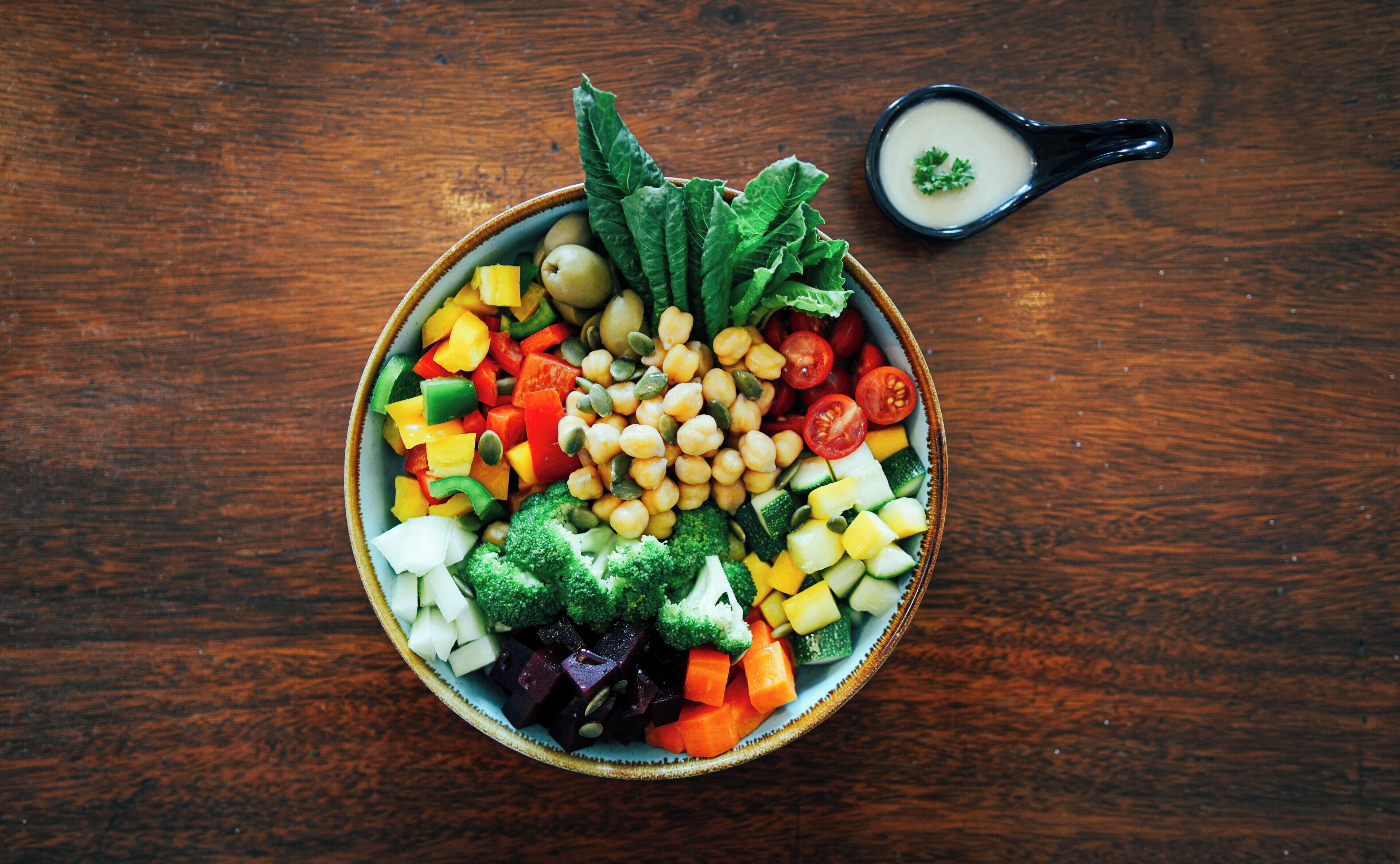 A bowl of mixed vegetables on a wooden table.