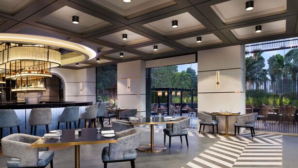 Een modern restaurant met een bar, zitplaatsen met ronde tafels en stoelen, en een vloer met een patroon.
