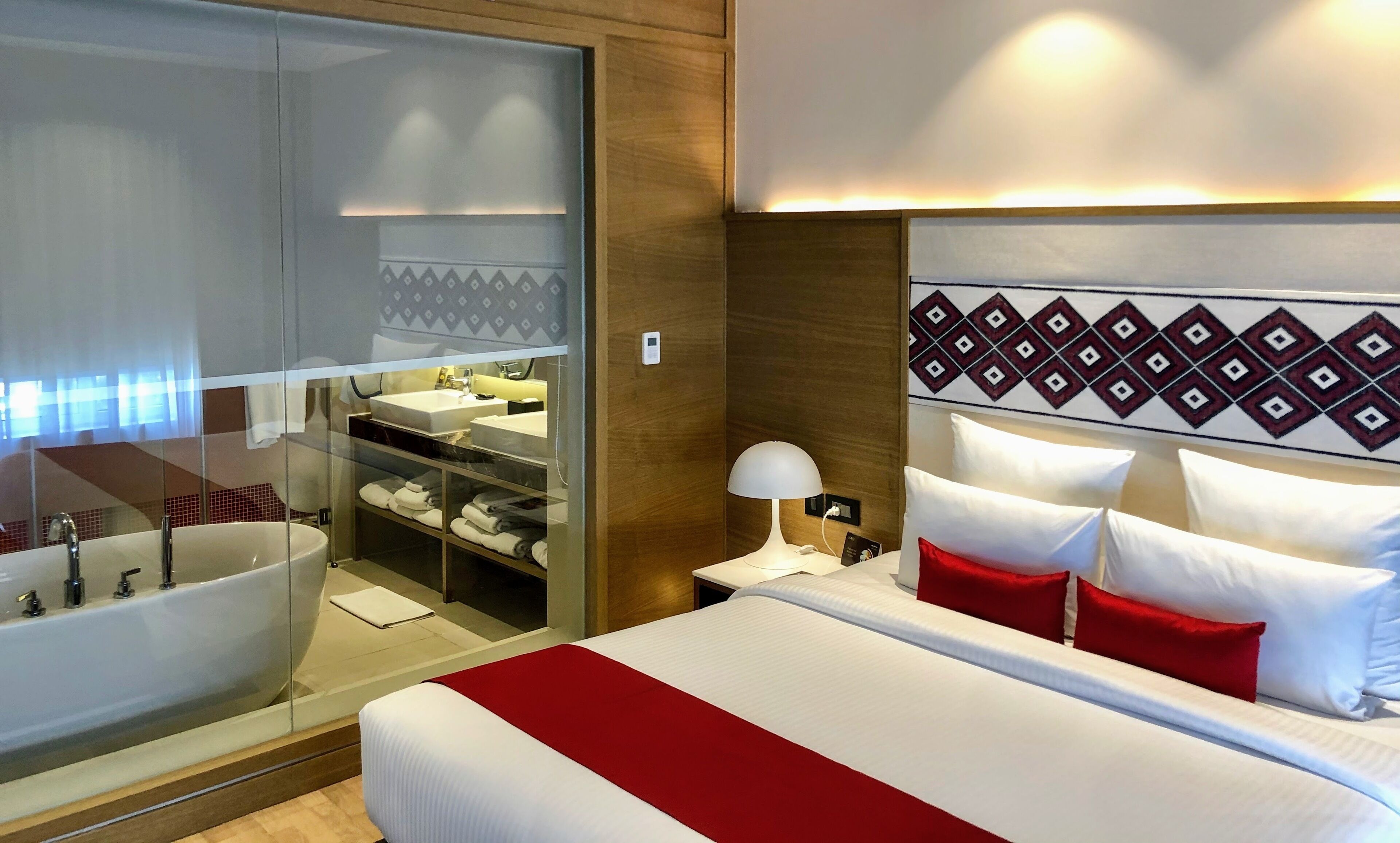 Une chambre d’hôtel avec un grand lit, une salle de bain séparée avec une baignoire et une armoire avec des étagères.