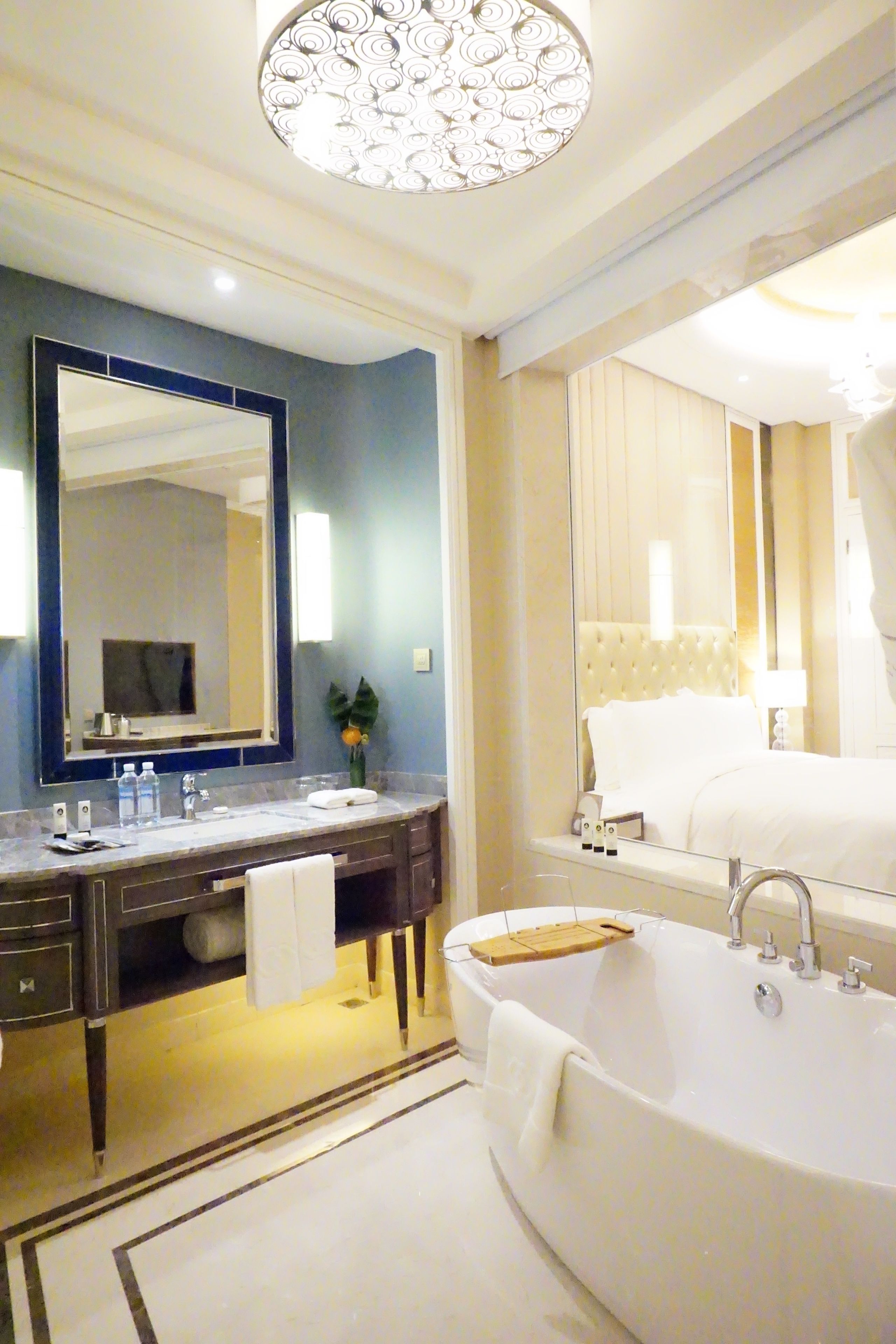 Une salle de bain moderne avec un grand miroir, une baignoire et un meuble-lavabo doté d’un porte-serviettes.