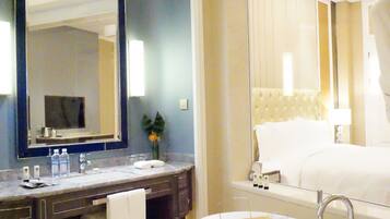 Une salle de bain moderne avec un grand miroir, une baignoire et un meuble-lavabo doté d’un porte-serviettes.