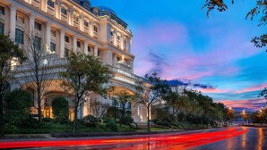 Un magnifique hôtel à l’architecture classique, doté d’un jardin bien entretenu et situé sur une rue mouillée où se reflètent les lumières.