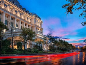 A grand hotel with classical architecture, a well-maintained garden, and a wet street reflecting lights. - Sofitel Shanghai Hongqiao (Shanghai)