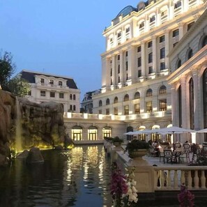 Un edificio imponente con diversi piani, un cortile con una fontana e zone relax all'aperto.