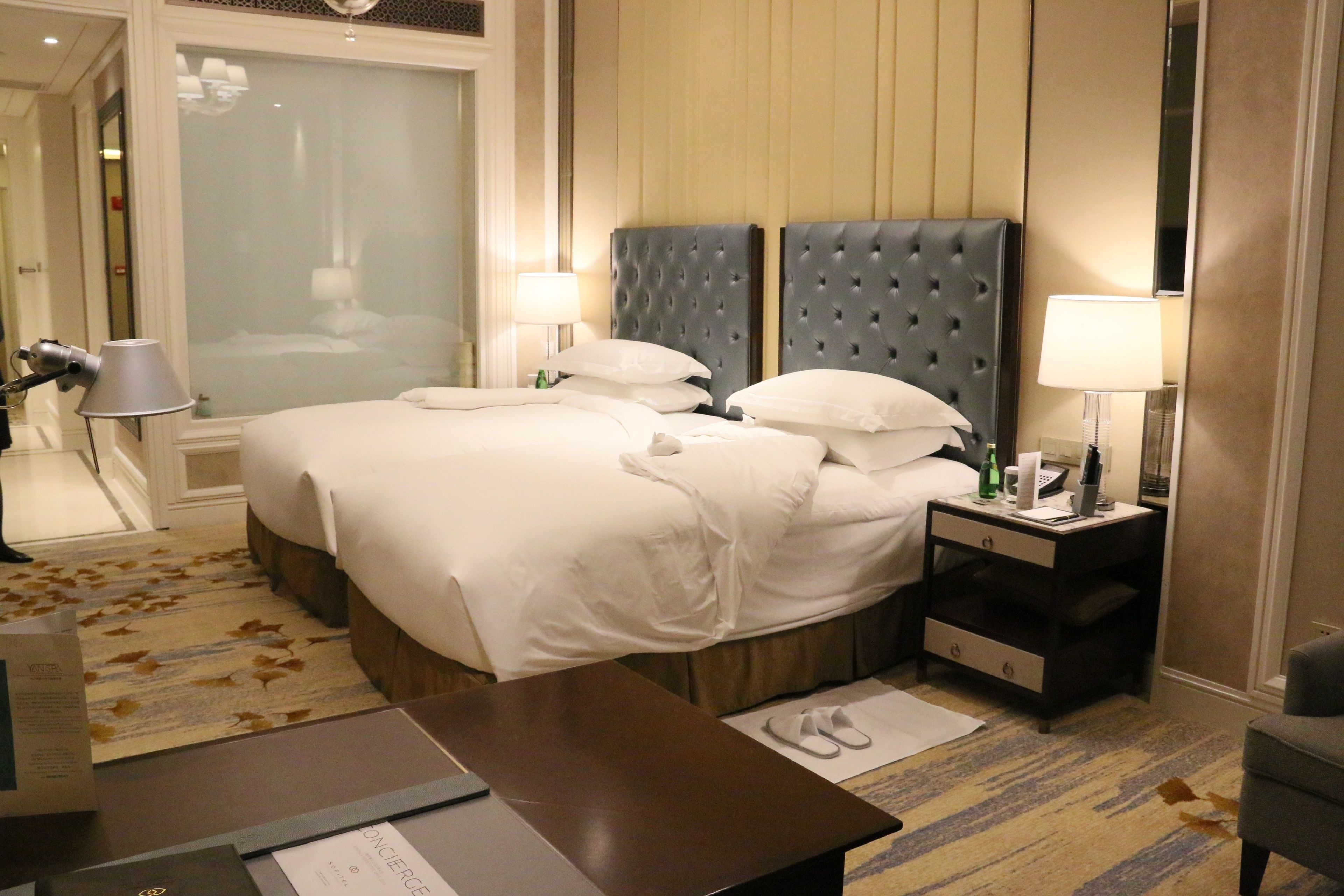 A hotel room with a large bed, two bedside tables, a nightstand, a chair, and a carpeted floor.