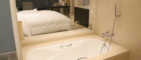 Une salle de bain d’hôtel avec une grande baignoire, un miroir et un meuble-lavabo.