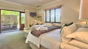 Een slaapkamer met een groot bed, een bureau, een stoel en een raam met zonwering.