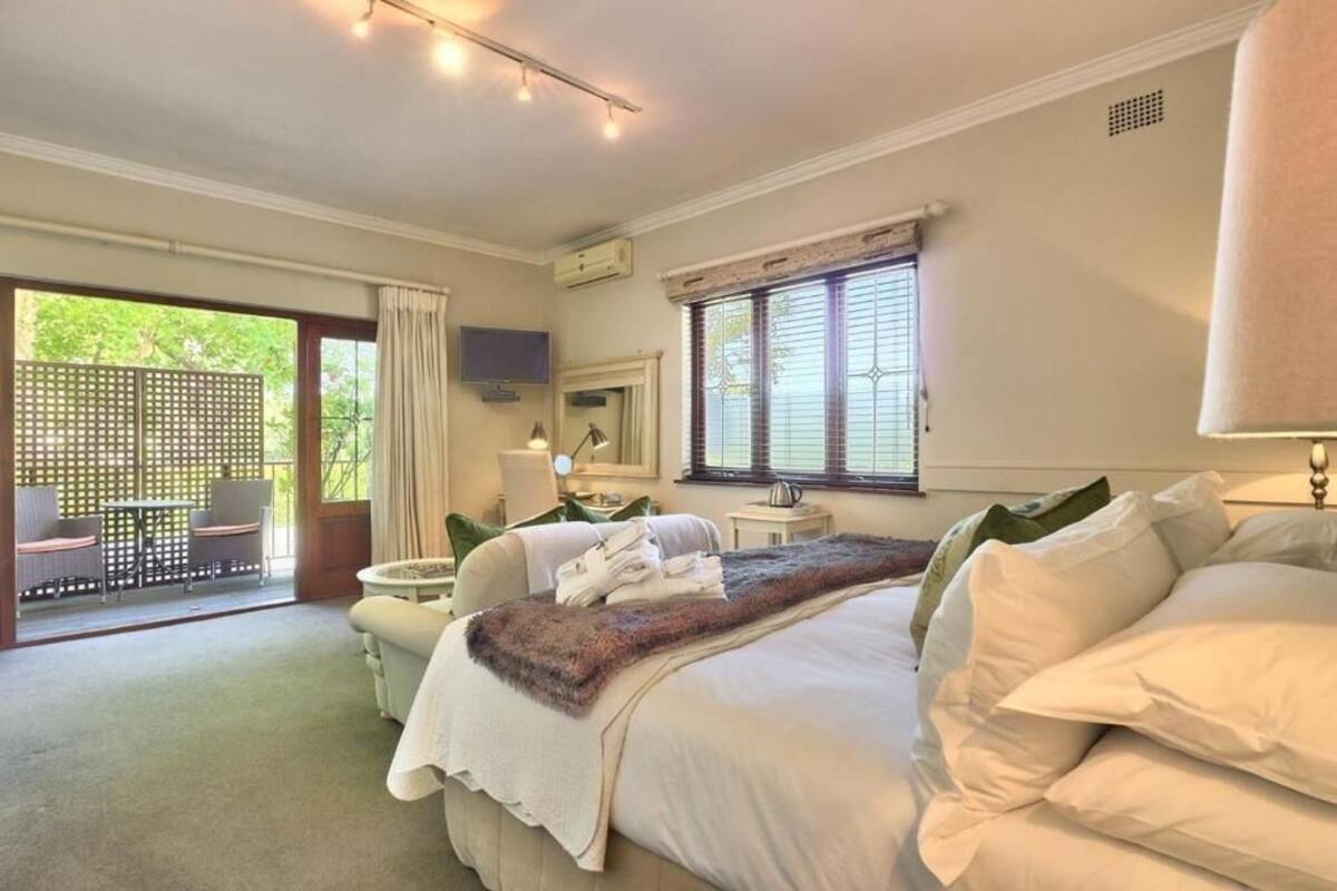 Ein Schlafzimmer mit einem großen Bett, einem Schreibtisch, einem Stuhl und einem Fenster mit Jalousien.