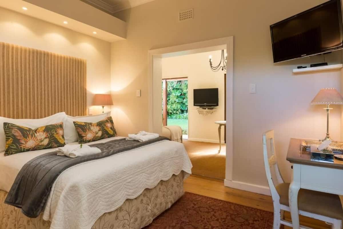 Ein Schlafzimmer mit Bett, Schreibtisch, Fernseher und einer Tür, die auf einen Balkon führt.