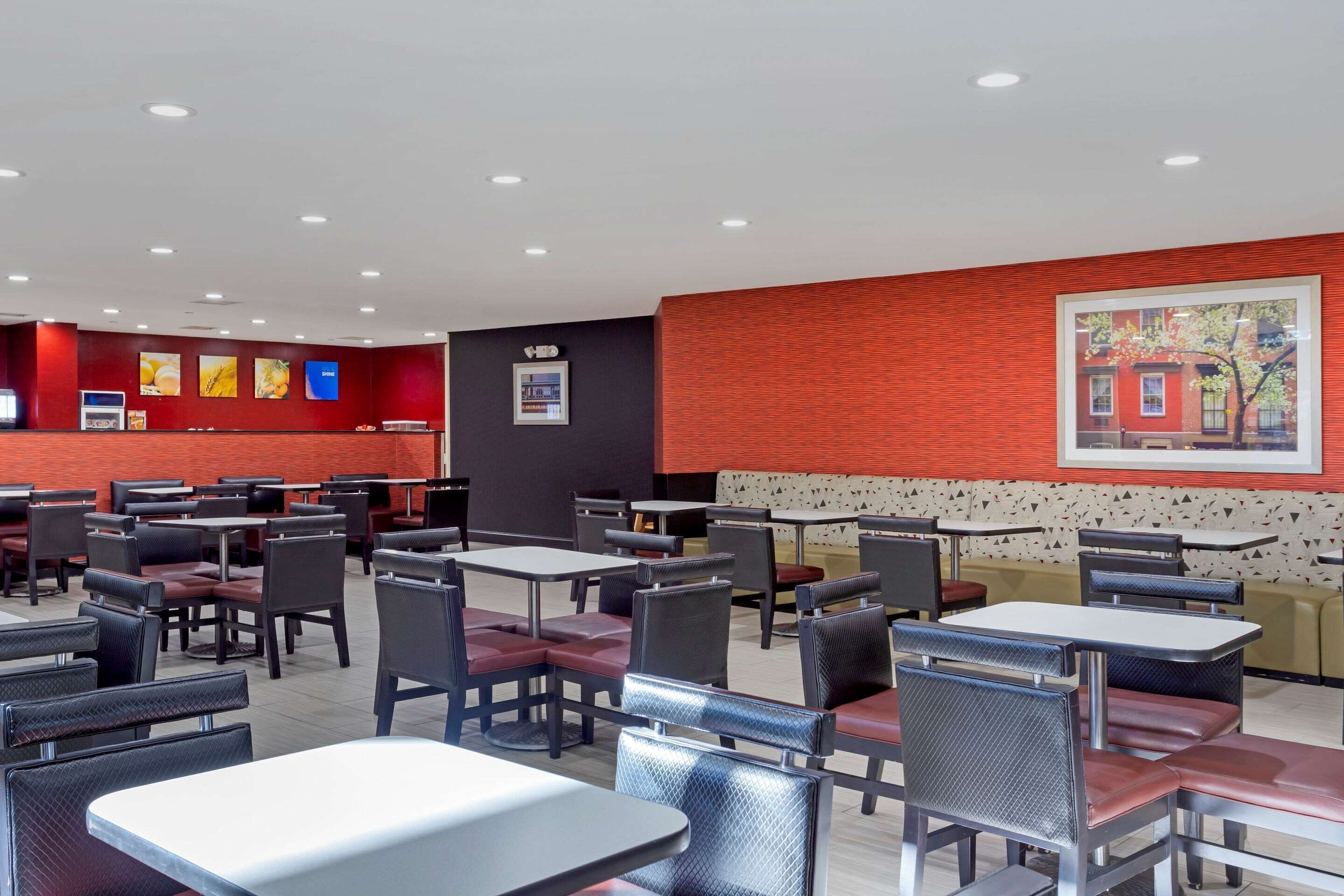 Un restaurante con varias mesas y cabinas, una pared de acento roja y un cuadro en la pared.