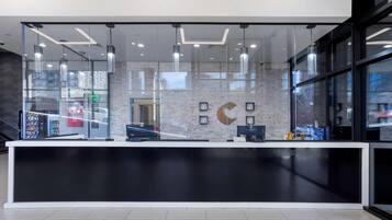 A modern reception desk with a glass partition, a computer, and a cash register.