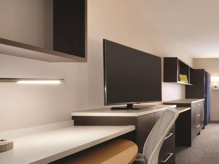 Een moderne hotelkamer met een flatscreen televisie, een bureau en een stoel.